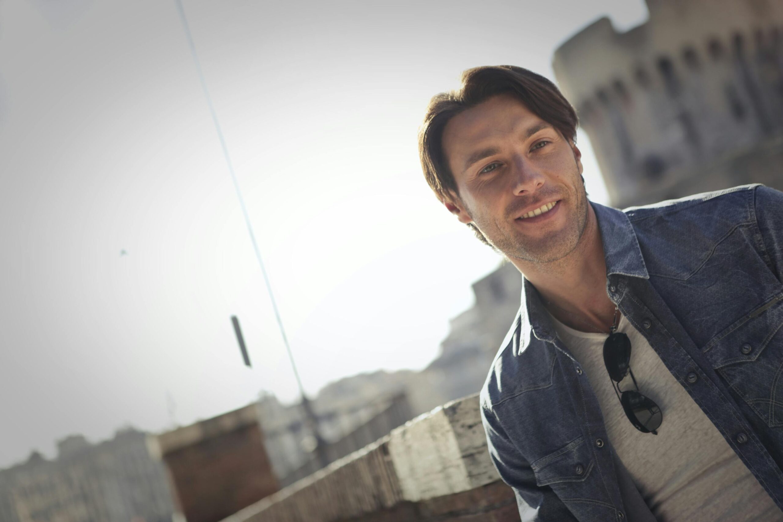 Portrait of a trendy young man smiling on a rooftop with urban background.